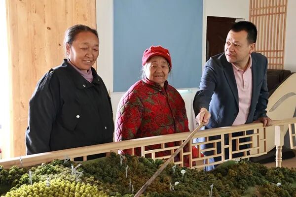 余廷学(右一)在沙盘前为村民讲述吉星村发展规划