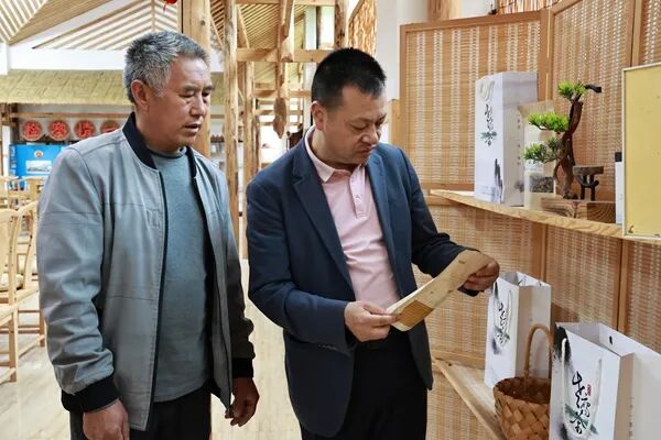 余廷学(右)和村民一起探讨老鹰茶下一步发展规划